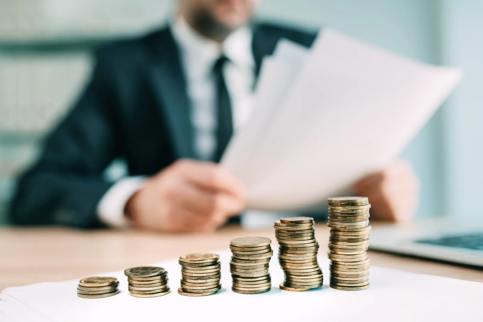 Pièces de monnaie empilées sur un bureau, à côté de documents